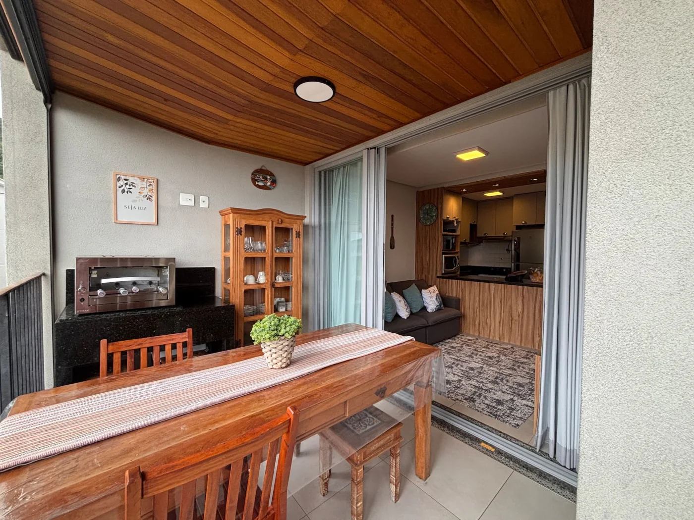 A cozinha completa, planejada com marcenaria e equipada com eletrodomésticos modernos, integrando a sala de estar, criando uma conexão com a área gourmet. A integração dos espaços valoriza a