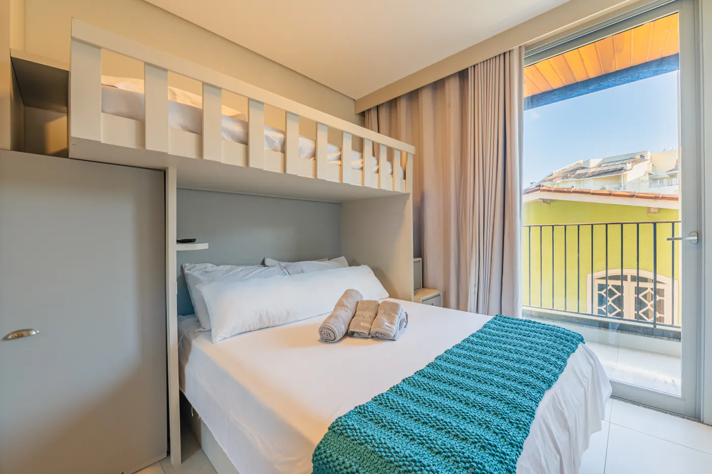 Quarto com cama de casal e beliche, ao lado da sacada