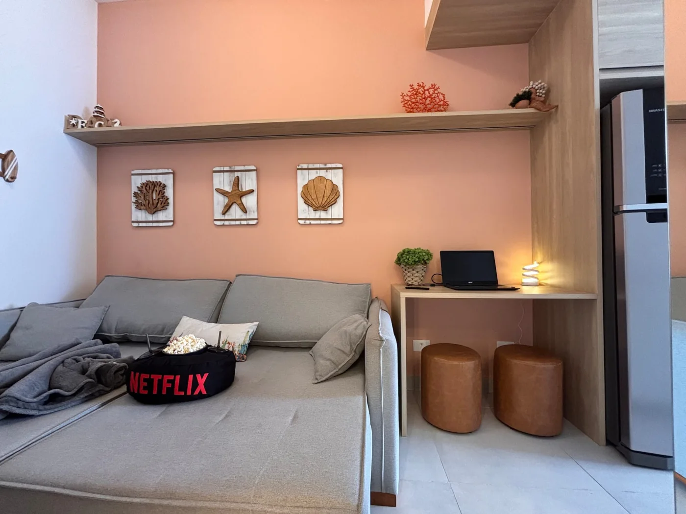 Um ambiente decorado em estilo praiano é composto por um sofá cama casal para o aconchego do casal após um dia de praia relaxar e assistir um filme!