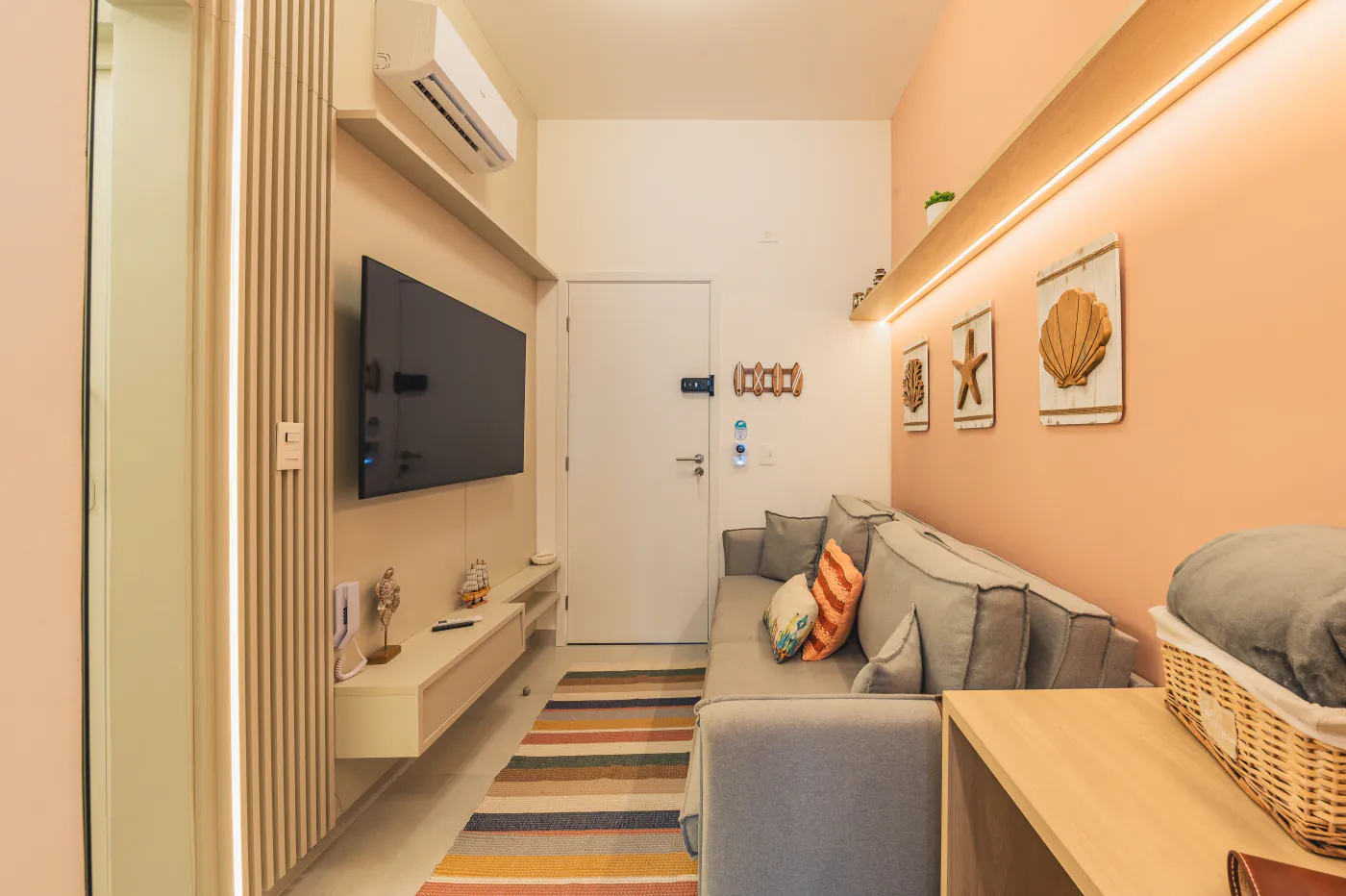 Sala com sofá, painel de TV e decoração praiana