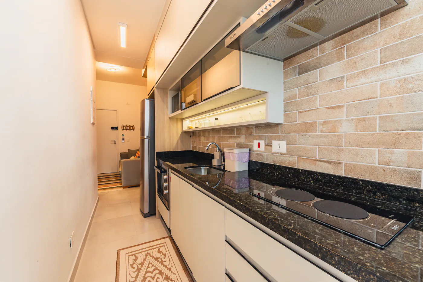 Cozinha com bancada de granito, cooktop e coifa