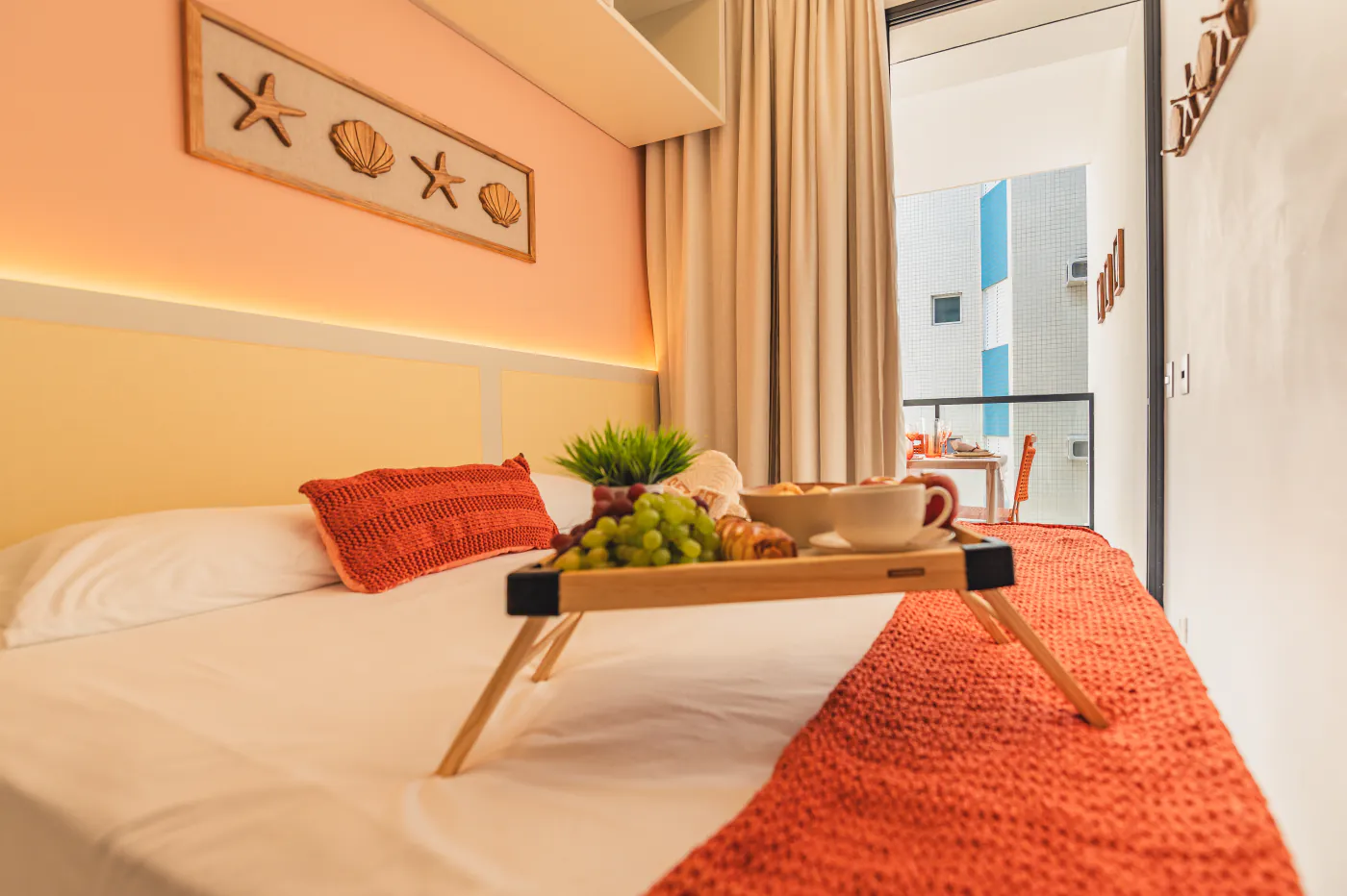 Quarto com cama de casal, cortinas e acesso à varanda