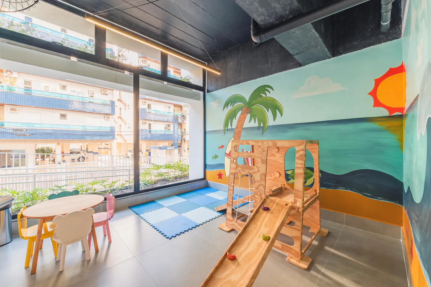 Brinquedoteca com painel lúdico de praia, tatame e brinquedos de madeira