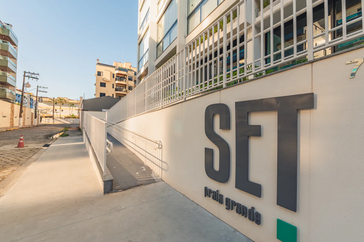 Entrada do Condomínio SetPG com a placa SET Praia Grande e rampa de acesso